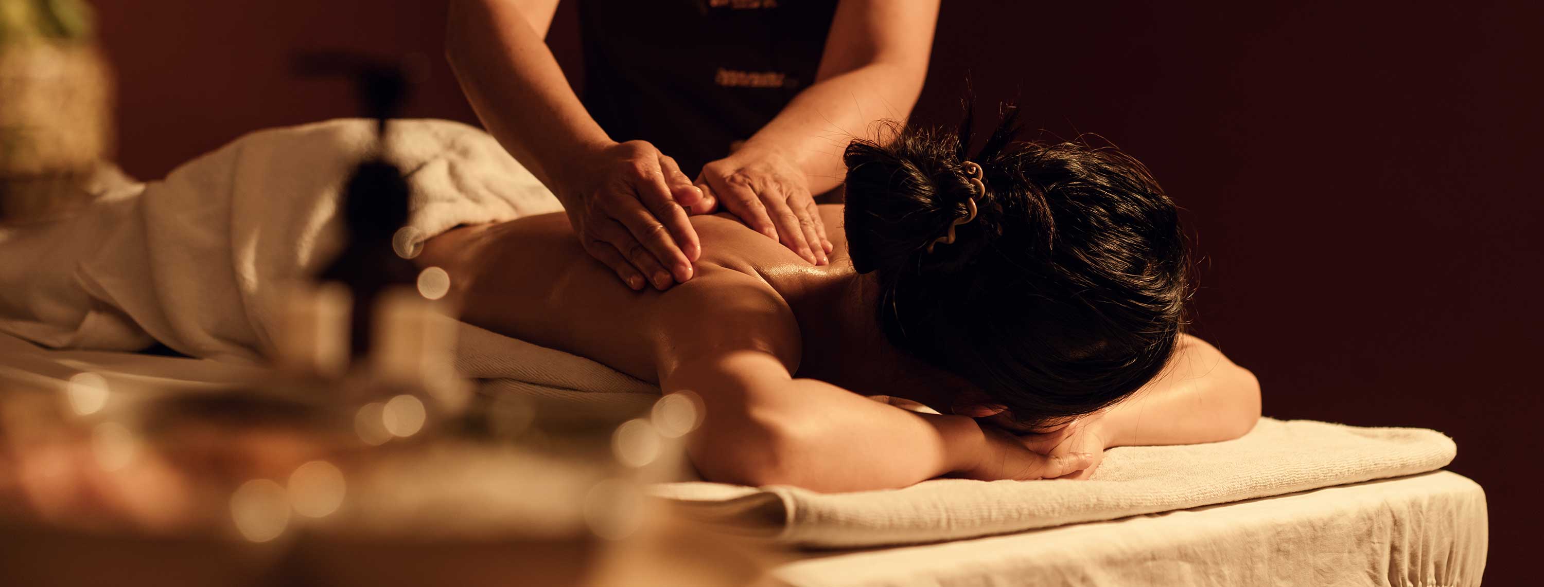 Frau wird auf der Liege massiert Frau erhält eine entspannende Rückenmassage auf einer Wellness-Liege mit weichem Handtuch.